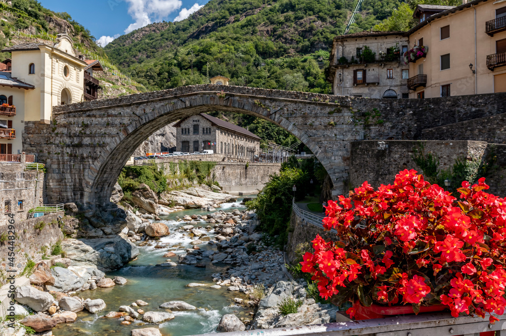 Beautiful red flowers decorate the historic center of Pont Saint Martin, Valle d'Aosta, Italy, near the ancient Roman bridge
