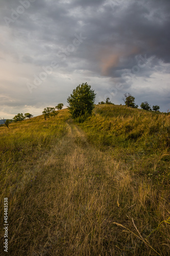 Dawn in the mountains. Path in the mountains at dawn.The sun rises from behind the mountains. Beautiful green and yellow hills. A colorful cloudy sky. Mountains in the fog. Carpathian  Ukraine 