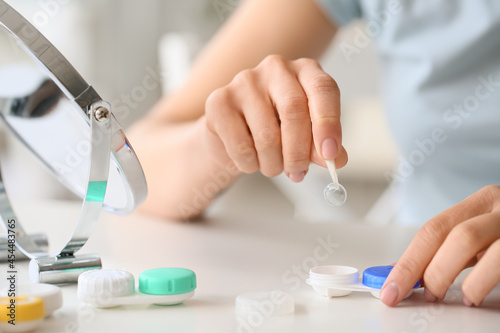 Young woman putting in contact lenses at ophthalmologist's office