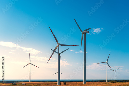 Windmills generating electricity located on a hill in the coastal area, the Baltic Sea in the background, wind farm against the blue sky, Poland Europe