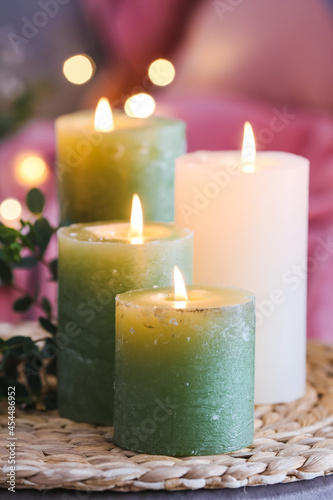 Beautiful burning candles on wicker mat  closeup