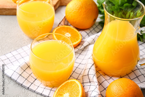 jug and glasses of tasty orange juice on light background  closeup