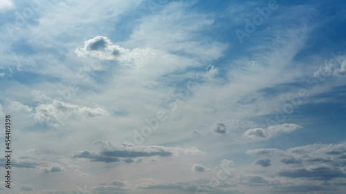 White clouds fast moving on blue sky. Time lapse with sunbeams and shadows at sunny day. Beautiful cloudscape background. 