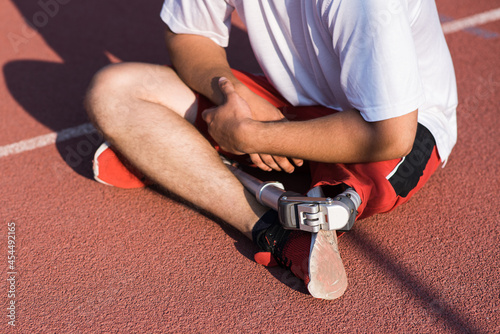 Close up of a Caucasian male with a prosthesis on his leg sitting on the track.