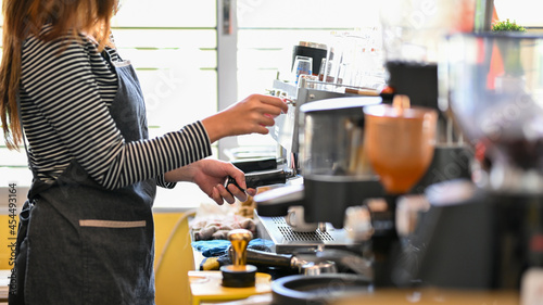 Cropped image of female barista making coffee by coffee machine