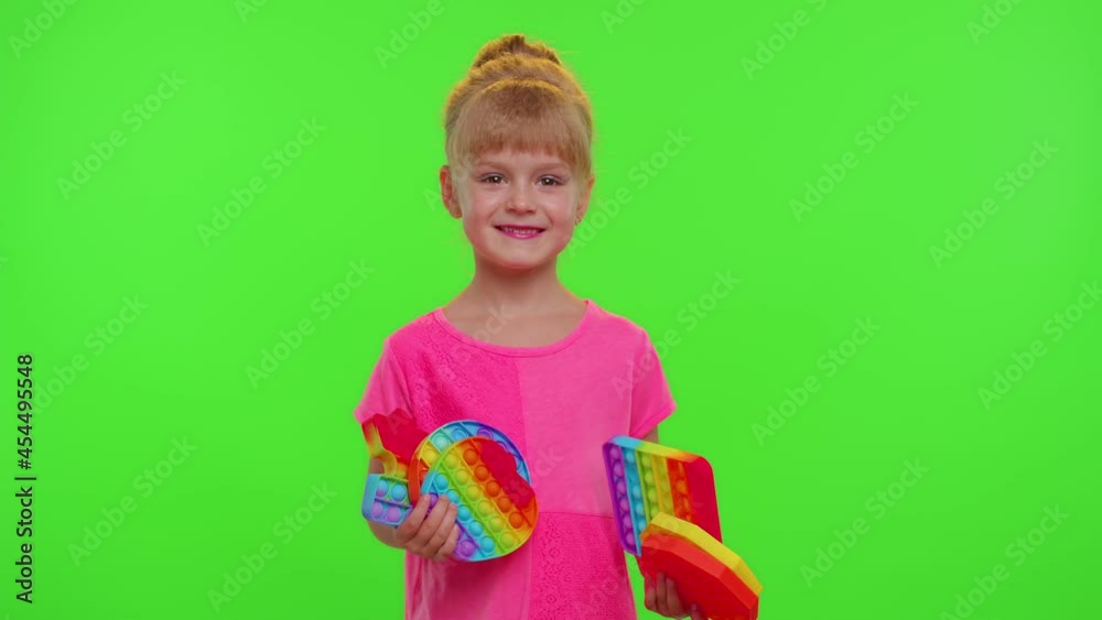 Stylish little child kid showing pop it sensory toy. Girl with colored rainbow squishy soft silicone touch screen bubbles. Stress anxiety relief. Trendy fidgeting game for stressed children and adults Stylish little child kid showing pop it sensory toy. Girl with colored rainbow squishy soft silicone touch screen bubbles. Stress anxiety relief. Trendy fidgeting game for stressed children and adults