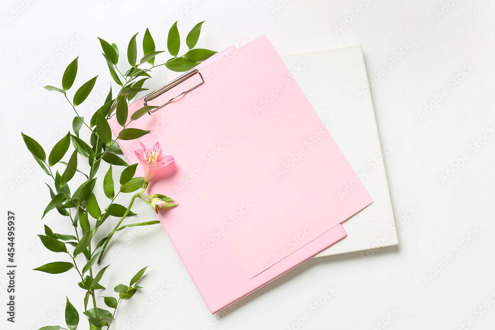 Clipboard with blank sheet of paper, poster, flower and plant branch on white background