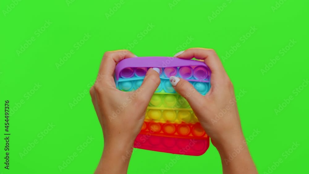 Close-up of girl hands playing squeezing anti-stress toys simple dimple game isolated on chroma key. Popular educational pop it touch screen game with buttons. Autism Special Needs Stress Reliever