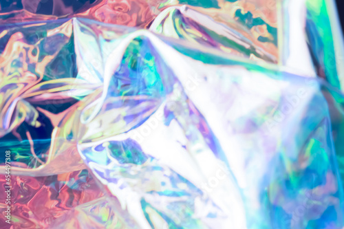 Defocused iridescent holographic background. Blurred colorful texture of wrinkled foil.