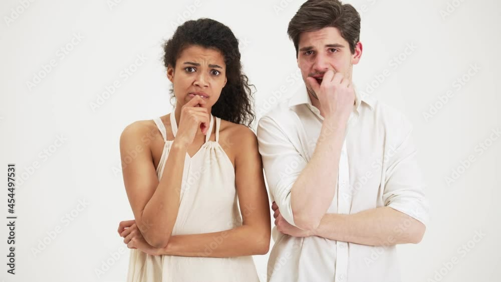 Nervous couple looking to the camera while waiting for result standing isolated over a white background in the studio Nervous couple looking to the camera while waiting for result standing isolated over a white background in the studio