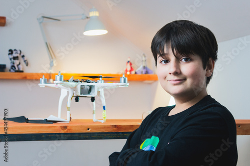Advanced work in physics. Smart collaboration. A teenager with a smile on his face and folded hands on his chest in front of the drone he has assembled.