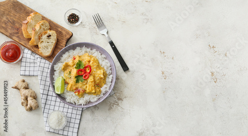 Bowl of tasty chicken curry with rice and ingredients on light background