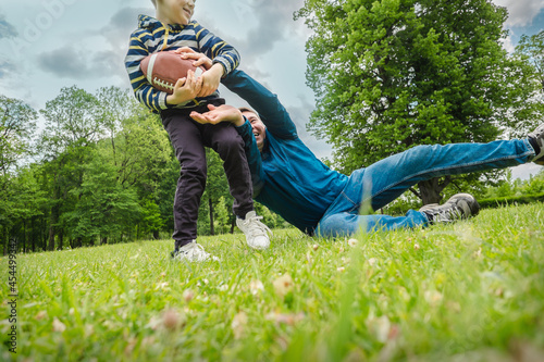 Father and son playing football, Father's day, Playful Man teaching Boy rugby outdoors in sunny day at public park. Family sports weekend. 