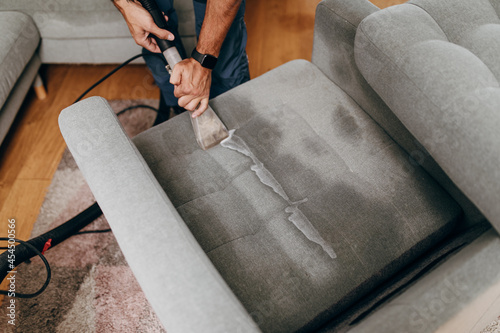 Slika na platnu Handsome young man cleaning furniture