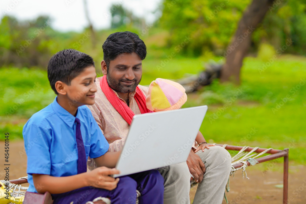 Obraz premium Education concept :cute indian school boy using laptop and giving some information to his father.