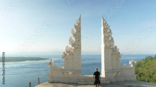 Man in kilt walk and stays in balinesse hindu gate in front of ocean in Bali Indonesia. High quality 4k footage photo