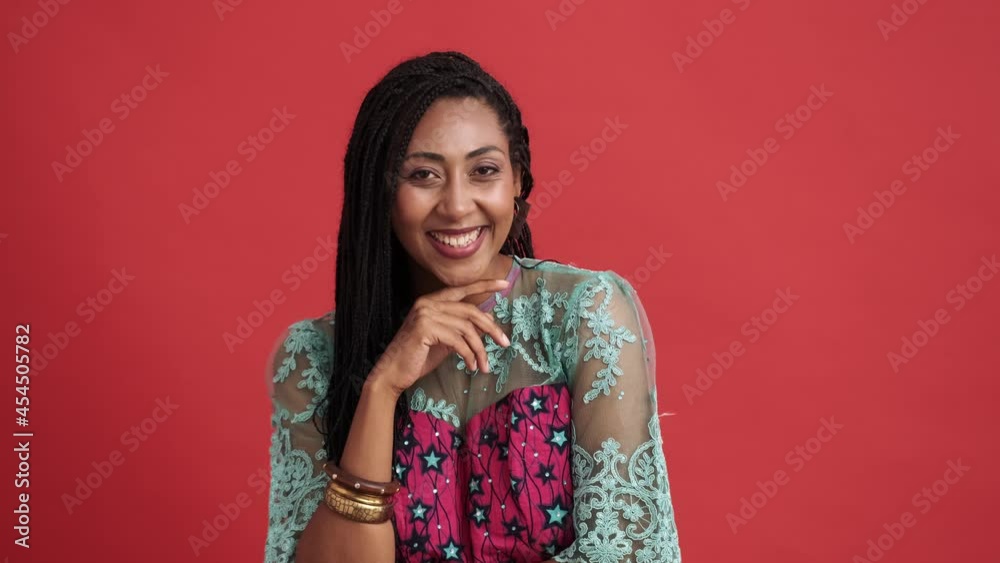 A happy african american woman laughing looking to the camera standing isolated over red background in the studio