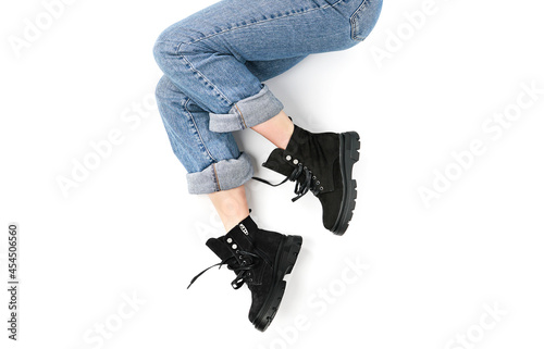 legs of a girl in jeans and black leather shoes on a white background top view. fashion shoes autumn spring 2022