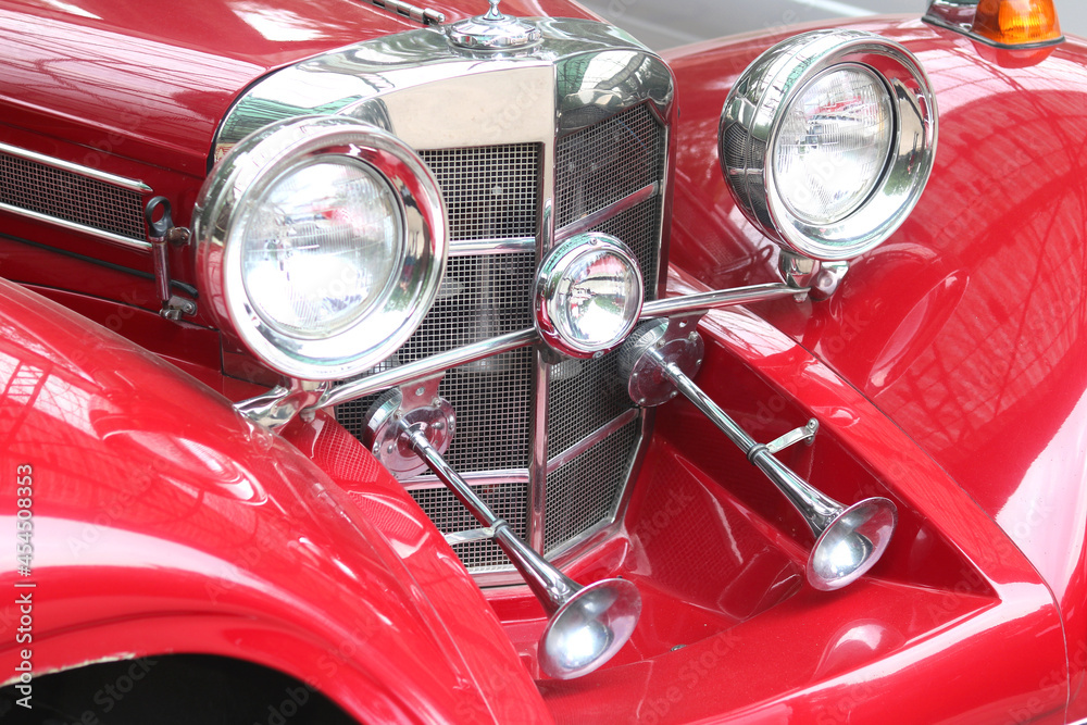 Front of old red car close up with round car headlights
