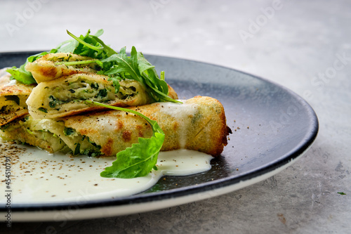 Closeup view of thin crepe stuffed with cheese, arugula and spinach