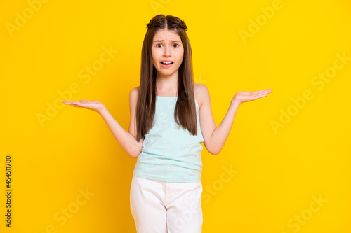 Photo of nice unhappy little girl hold hands empty space scales choose object isolated on yellow color background