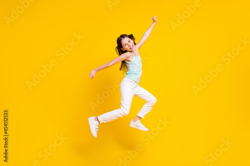 Full size profile side photo of cheerful crazy little girl jump up air good mood isolated on bright yellow color background