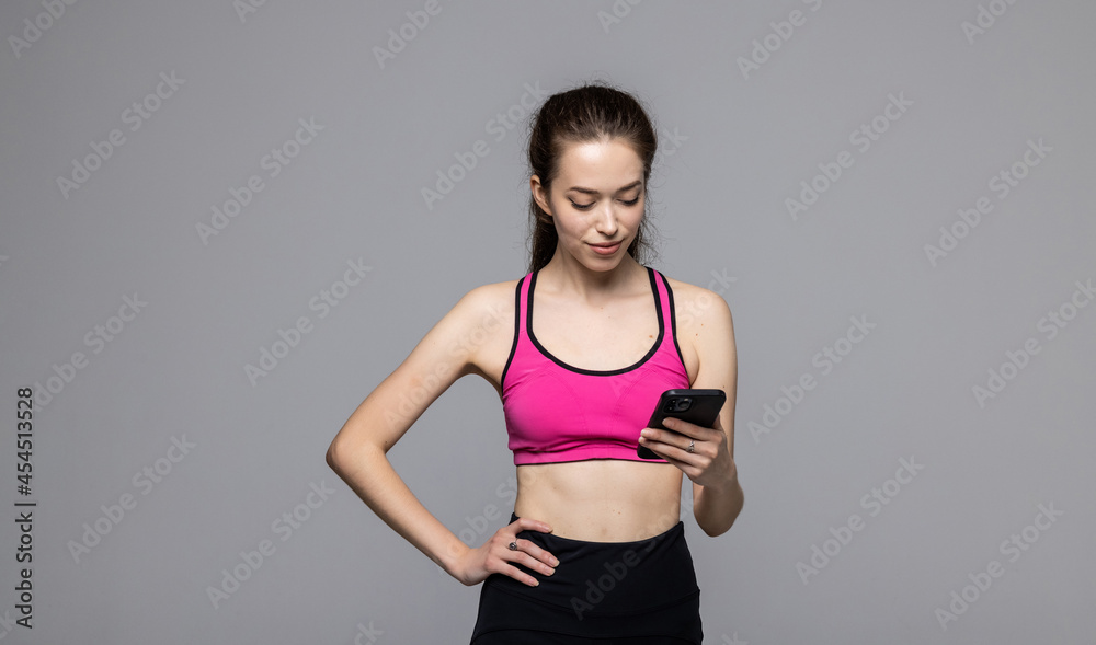 Portrait of young sport woman waring sport bra and leggings use smartphone over white background. Female holding phone and chat. Portrait of young sport woman waring sport bra and leggings use smartphone over white background. Female holding phone and chat.