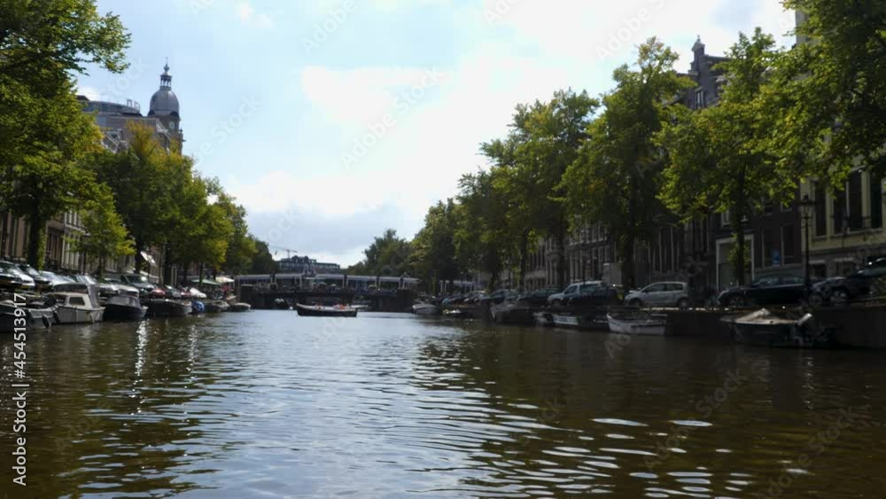 Riding in a boat along houses in Amsterdam on a canal in summer on sunny day. Riding in a boat along houses in Amsterdam on a canal in summer on sunny day.