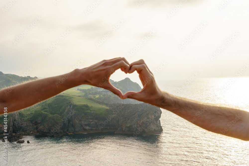 Horizontal close up of unrecognizable couple holding hands in heart shape framing travel destination Horizontal close up of unrecognizable couple holding hands in heart shape framing travel destination