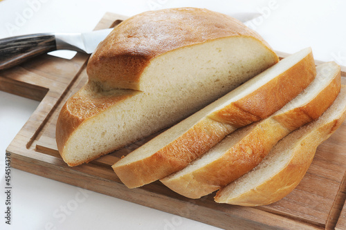 round bread cut into slices on a wooden board with a knife