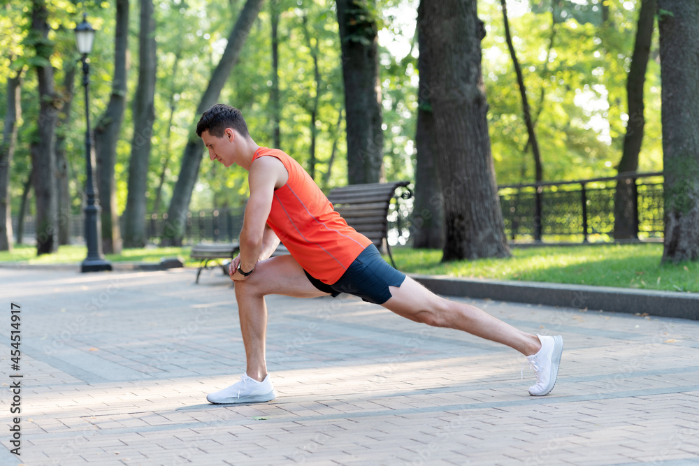 Sportsman hold lunge position doing stretch routine during outdoor athletic workout in park, warmup Sportsman hold lunge position doing stretch routine during outdoor athletic workout in park, warmup
