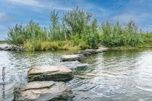 stepping stones in water, maas river, den bosch, 's-hertogenbosch with blue sky
