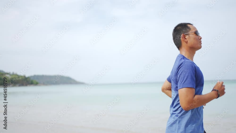 4K Healthy Asian man in sportswear jogging or running on the beach by the sea in summer morning. Strong athlete male do sport training workout fitness on the beach with listen to music from smartphone 4K Healthy Asian man in sportswear jogging or running on the beach by the sea in summer morning. Strong athlete male do sport training workout fitness on the beach with listen to music from smartphone