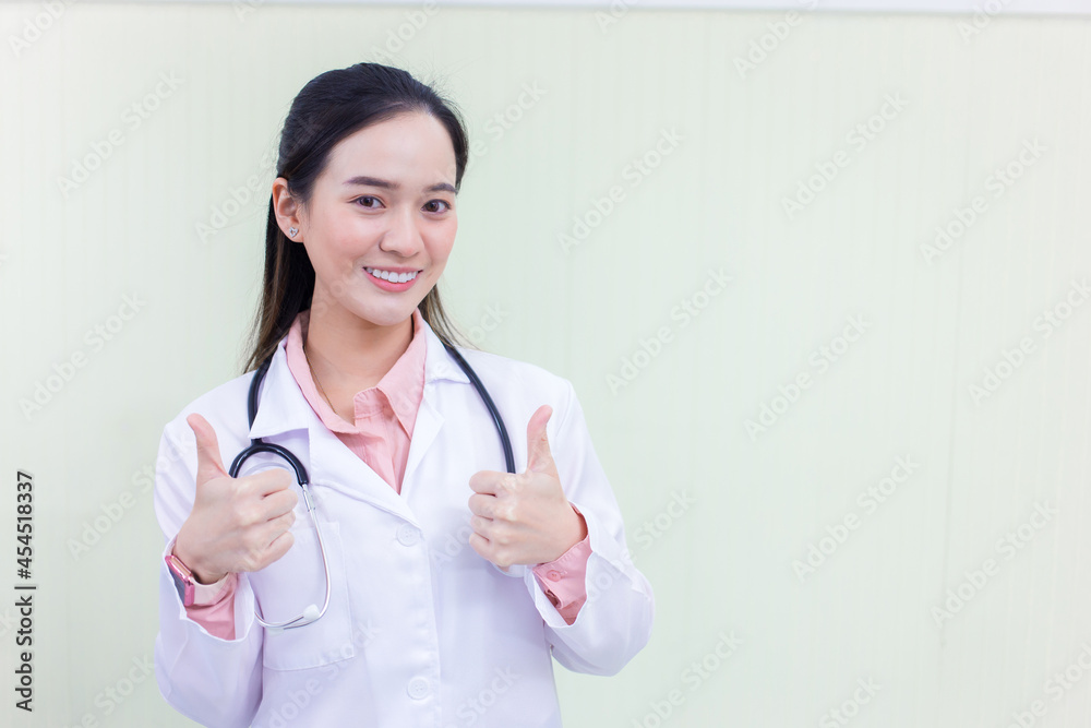 Asian young woman doctor who wears medical uniform is showing hand as thump up on white background. Asian young woman doctor who wears medical uniform is showing hand as thump up on white background.