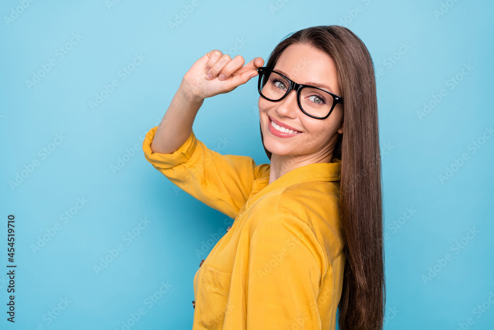 Profile side photo of young attractive pretty girl happy positive smile hand touch eyeglasses cool isolated over blue color background Profile side photo of young attractive pretty girl happy positive smile hand touch eyeglasses cool isolated over blue color background