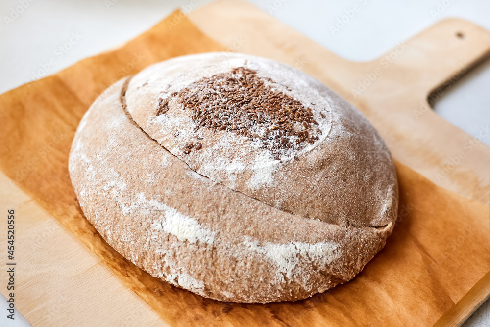 Homemade round rye bread with flax seeds on a wooden board. Close-up, selective focus Homemade round rye bread with flax seeds on a wooden board. Close-up, selective focus