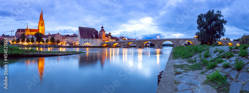 Regensburg. Old stone bridge over the Danube river at night light.