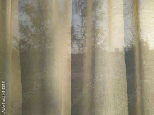 white curtains on the window and the light of the sun at sunset. © Левон Мартиросян