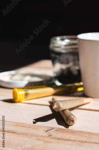 Close-up of two cannabis joint on wooden table next to a cup of coffee. Concept of therapeutic cannabis, medical cannabis, legal cannabis
