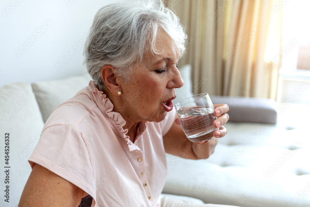 Cropped shot of a woman drink pure clean mineral water from glass, for body refreshment and good health. Mature grandmother feel thirsty enjoy clean still aqua for hydration, healthy lifestyle concept Cropped shot of a woman drink pure clean mineral water from glass, for body refreshment and good health. Mature grandmother feel thirsty enjoy clean still aqua for hydration, healthy lifestyle concept