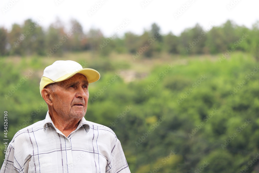 Portrait of elderly man on green mountain background. Life in village, travel in old age Portrait of elderly man on green mountain background. Life in village, travel in old age