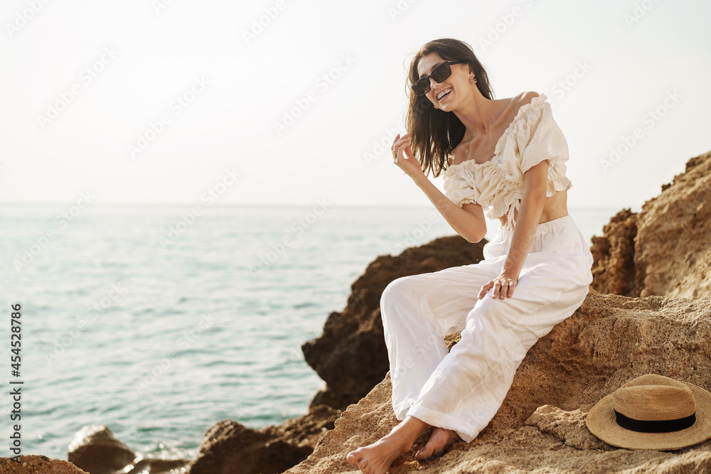 Woman traveler sitting near sea on cliff injoying view of sea and nature