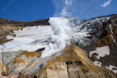 a valley of fumaroles with an eruption of water vapor and sulfur. Climbing the Mutnovsky volcano. Kamchatka Peninsula.