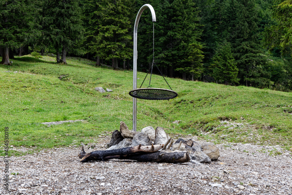 metal fire grill station on a gravel place in front of a green fir forest the fire has gone out