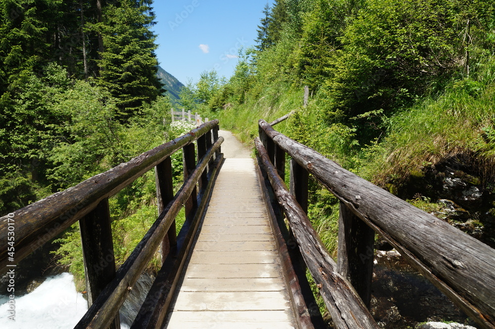 a wooden bridge over an alpine creek in the Schladming-Dachstein region in Austria a wooden bridge over an alpine creek in the Schladming-Dachstein region in Austria