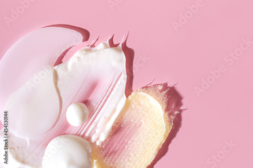 Various cosmetic mask, creams, serum, scrub and lotion smear on a pink background. Beauty texture. Sample of a cosmetic product.