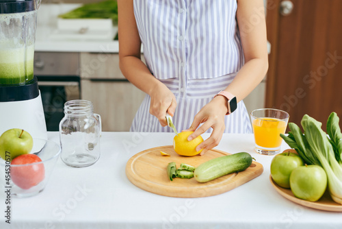 Woman cutting vegetable to make smoothie in the kitchen at home. Healthy concept.