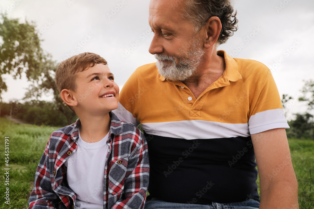 Fototapeta premium Cute little boy and grandfather spending time together in park