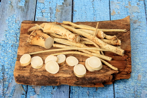 Cut Horseradish roots (Armoracia rusticana taproot) on rustic wooden board. Fresh horseradish.