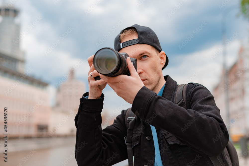Young focused millenial male photographer tries to make photo on professional camera outdoors Young focused millenial male photographer tries to make photo on professional camera outdoors